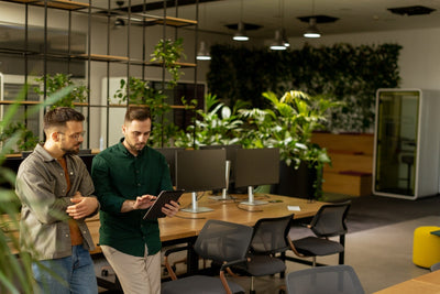 Due professionisti in un ufficio moderno con parete verde e piante, esempio di biophilic design