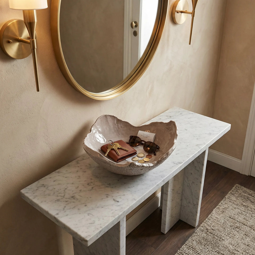 Ciotola in ceramica artigianale utilizzata come svuotatasche con chiavi e accessori su consolle in marmo