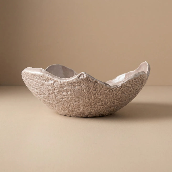 Ciotola grande in ceramica artigianale con bordo irregolare e texture naturale su sfondo beige