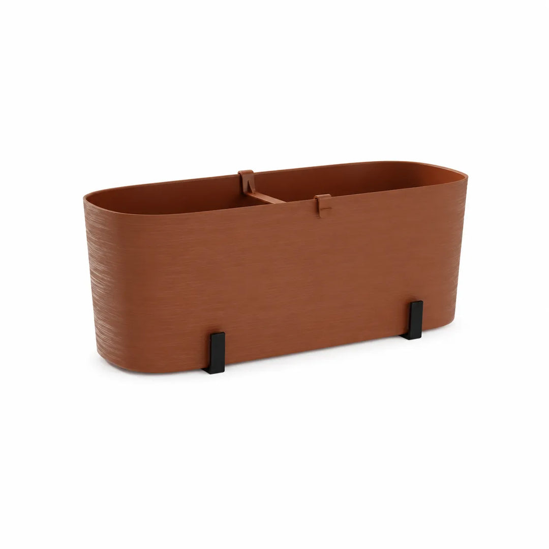 Fioriera Paros color terracotta con forma arrotondata, finitura effetto spazzolato e supporti integrati per esterni.