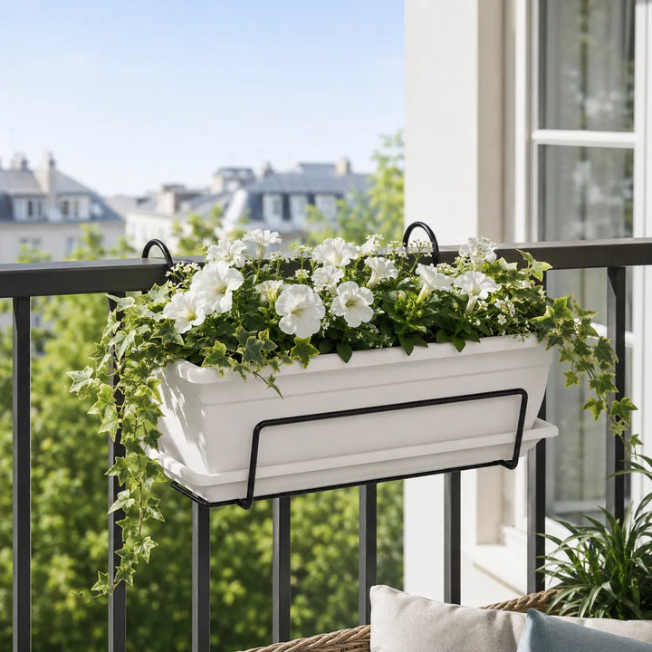 Fioriera da balcone Nara bianca con petunie bianche ed edera ricadente montata su parapetto esterno luminoso.