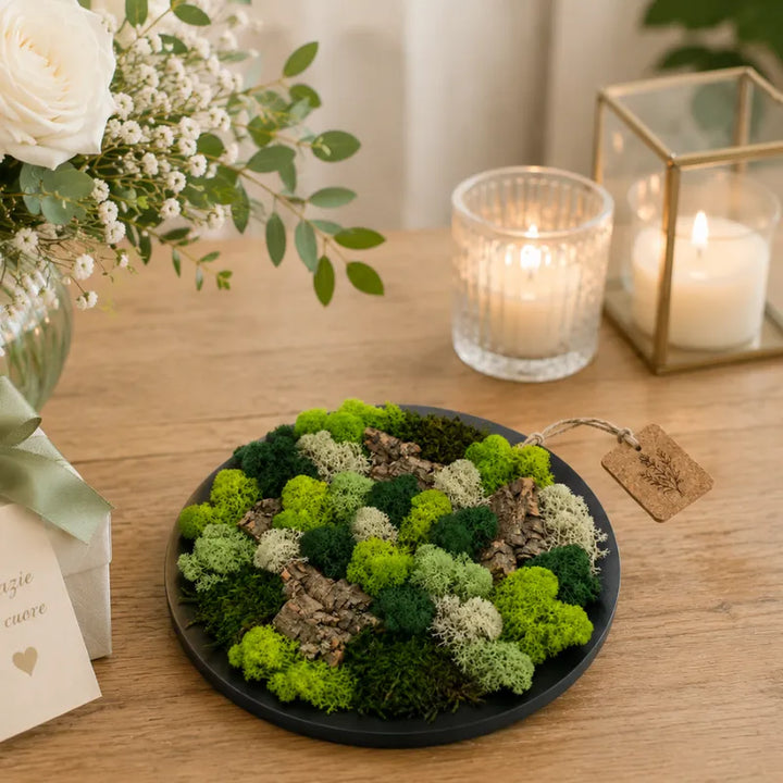 Quadro tondo nero con muschio e licheni stabilizzati utilizzato come decorazione green per matrimonio con candele, fiori bianchi e dettagli naturali raffinati.