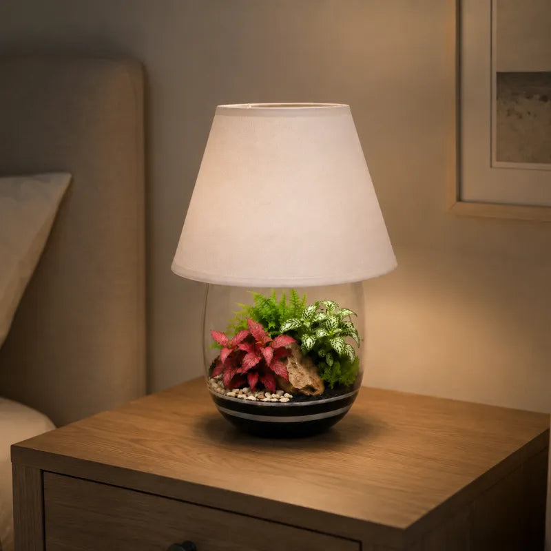 Lamparium Oasi Lux Elegant acceso su comodino in camera da letto, con terrarium di Fittonia e felci ideale come luce decorativa naturale.