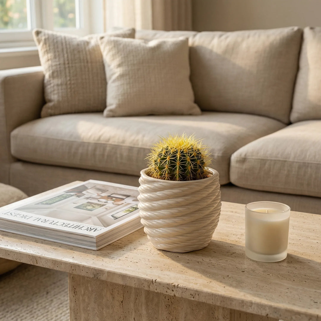 Vaso Carina in argilla con cactus su tavolino davanti a divano moderno con libro e candela