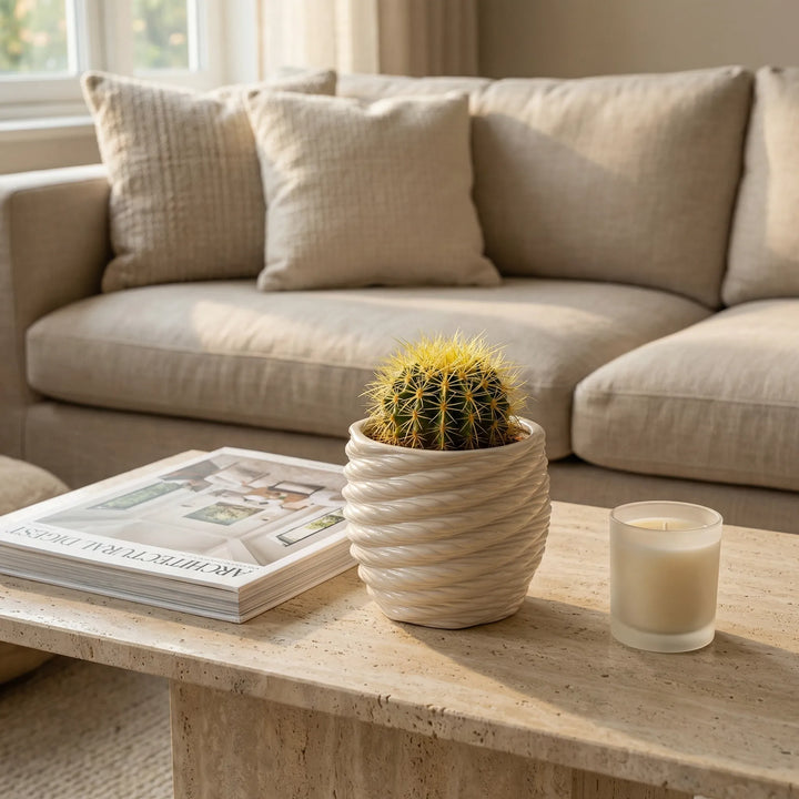 Vaso Carina in argilla con cactus su tavolino davanti a divano moderno con libro e candela