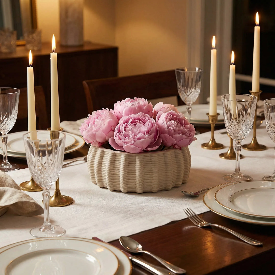 Vaso Dioniso in ceramica artigianale con peonie rosa su tavola apparecchiata con candele e bicchieri