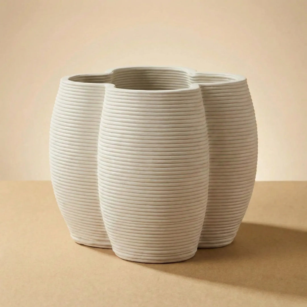 Vaso in ceramica beige dal design moderno con struttura ovale scanalata su sfondo neutro