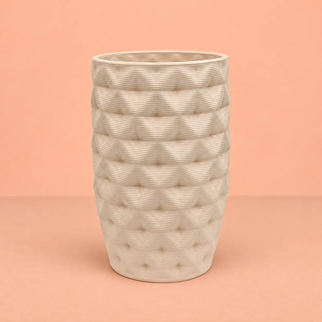 Vaso in argilla Rua alto Made in Italy, colore avorio con superficie lavorata a rilievo e forma leggermente affusolata, fotografato su sfondo pesca.