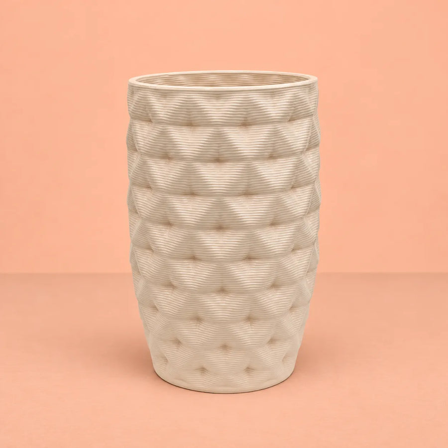 Vaso in argilla Rua alto Made in Italy, colore avorio con superficie lavorata a rilievo e forma leggermente affusolata, fotografato su sfondo pesca.