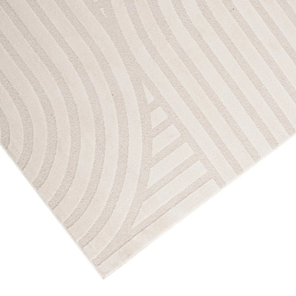 Dettaglio del tappeto avorio con superficie a rilievo e motivo a linee curve, tessitura elegante per ambienti contemporanei.

