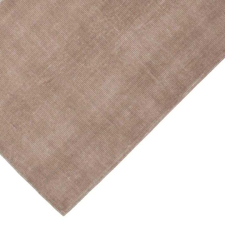 Dettaglio angolo tappeto tinta corda con finitura vellutata e lavorazione bouclé, perfetto per ambienti neutri e moderni